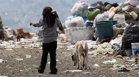 Una niña camina en un basurero