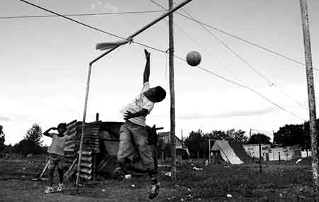 Två pojkar spelar boll i ett fattigt grannskap